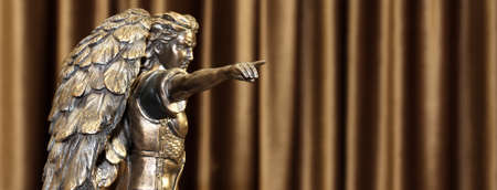 A bronze statuette of the Archangel Michael points a finger forward.の写真素材