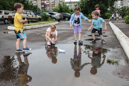 Children play with a puddle of paper boats. Donetsk 07/05/2020 Petrovsky district.のeditorial素材