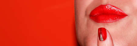 Red lipstick on her lips. Gender of a female face with makeup on an orange background.の写真素材
