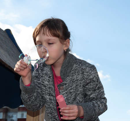 A girl blows soap bubbles against the sky. Children's games and entertainment.の写真素材