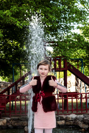 The child shows the class against the background of a fountain. Children Of Donbass. War and peace. Beautiful child.の写真素材