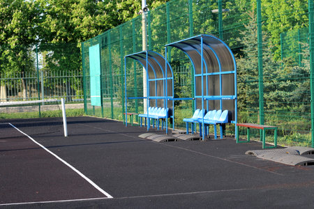 Tennis court against the background of trees. Seats on the tennis court.