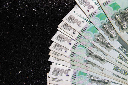 One thousand Russian rubles spread out in a fan on a black background. Savings of Russians.の写真素材