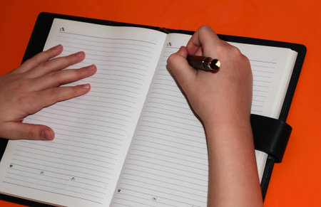 Notepad and children's pens with a pen on the orange table. Education at home.