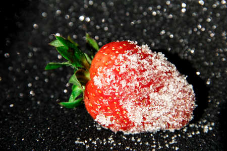 One strawberry in sugar on a black background. Berry in sugar.の写真素材