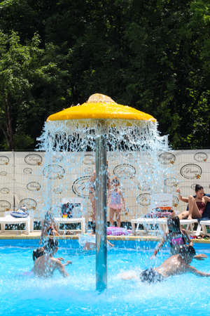 Children swim in the pool under the fountain.のeditorial素材