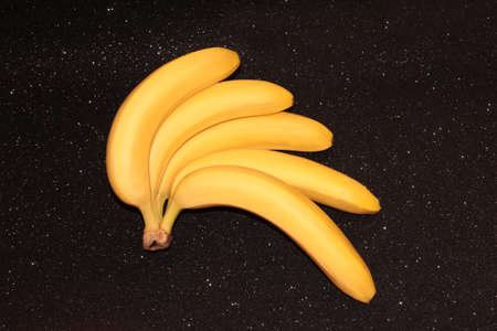 Bananas on a black background with bokeh and glitter. A fan of banana bunches.の写真素材