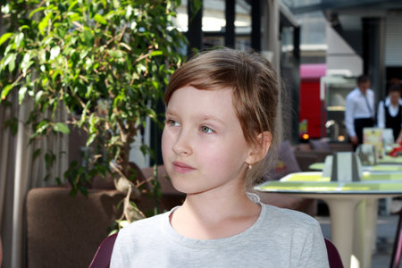 Portrait of a girl sitting in an outdoor restaurant.