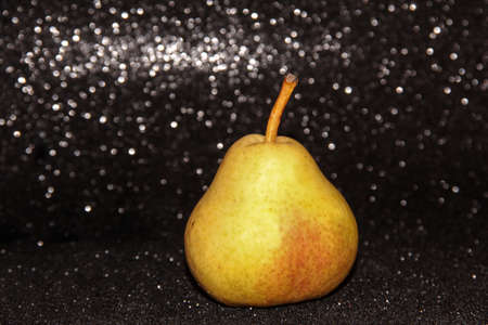 Yellow pear on a shiny black background.の写真素材