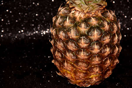 Part of a pineapple on a black shiny backgroundの写真素材