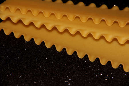 Pasta on a black shiny background. Lasagna sheets on a dark background. Food frame.の写真素材