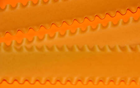 Macaroni on an orange background. The frame is bright. Flour products. The lasagna sheets.の写真素材