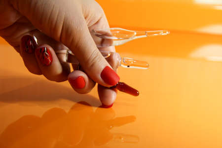 Medical ampoules in a woman's hand. Vaccination. Orange background with medications.の写真素材