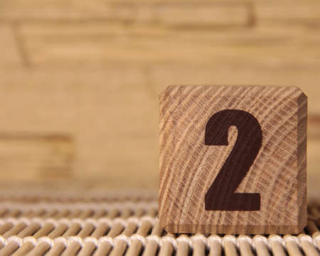Wooden cube with the number two on a beige background.の写真素材