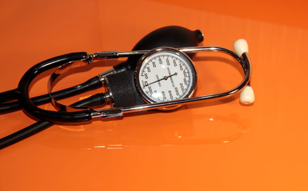 Blood pressure monitor on an orange background. Mechanical device for measuring pressure on a bright...