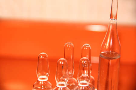 Ampoules for medicines on an orange background. Virus vaccine.の写真素材