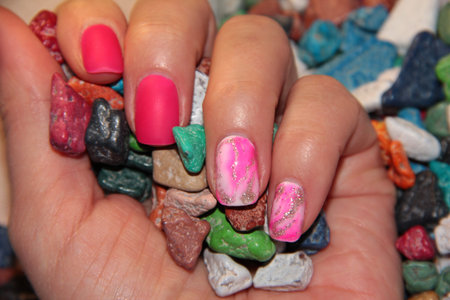 A woman's hand holds a pile of colored candies. Chocolate in the form of bright stones. Pink...