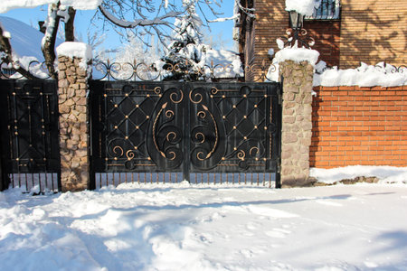Wrought iron gates with bronze elements. Red brick fence.