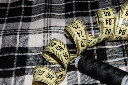 Background for needlework. On the checkered fabric scissors with threads and a measuring meterの写真素材