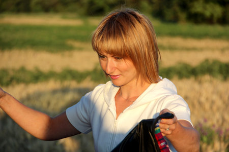 A girl in a field of wheat carries a blanket