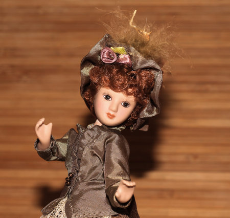 Doll of a girl in a beautiful vintage dress on a wooden background.の写真素材