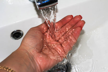 Water from the tap flows on a woman's hand. Hygiene of the person. Saving natural resources.