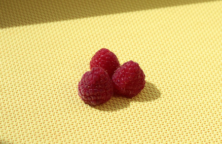 Three ripe raspberries on a green background.