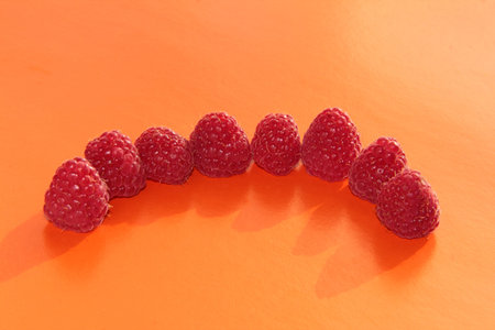 Berries on a bright background. Ripe raspberries on an orange background
