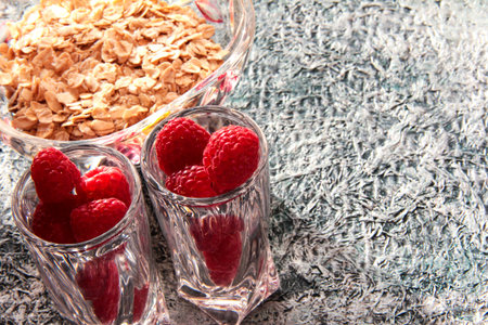 Raspberries in crystal stacks on a gray background. Breakfast with oatmeal.