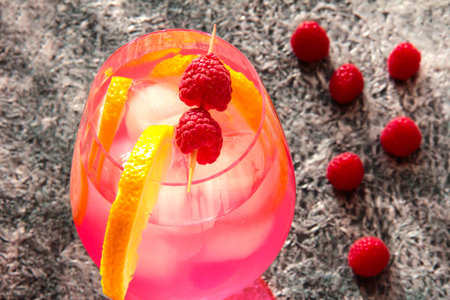 Raspberry drink in a glass with berries and lemon.