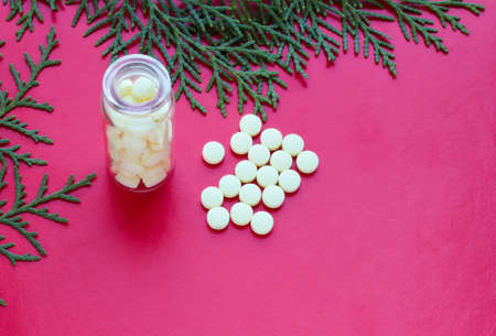 A bottle with yellow pills and a sprig of thuja on a purple background. Scattered vitamins.の写真素材