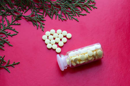 A bottle with yellow pills and a sprig of thuja on a purple background. Scattered vitamins.の写真素材