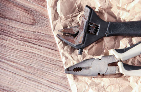Wrench with pliers on a wooden background with crumpled paper. Oldest tool.の写真素材