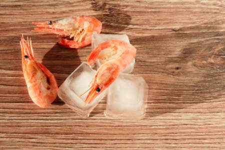 Frozen shrimp on ice on a wooden background.の写真素材