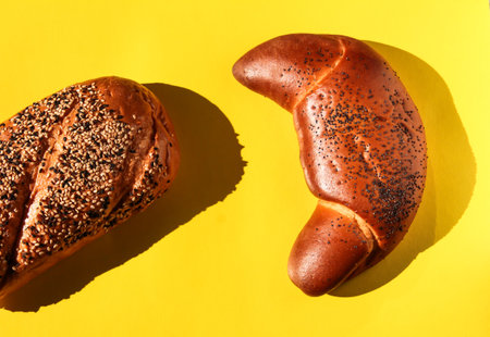 Freshly baked bread with poppy seeds on yellow background, top viewの写真素材