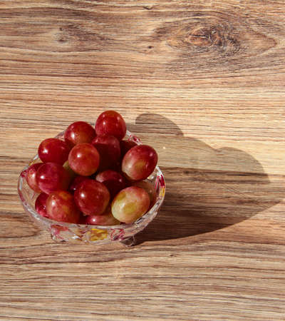 Grapes in a crystal bowl on a wooden background.の写真素材