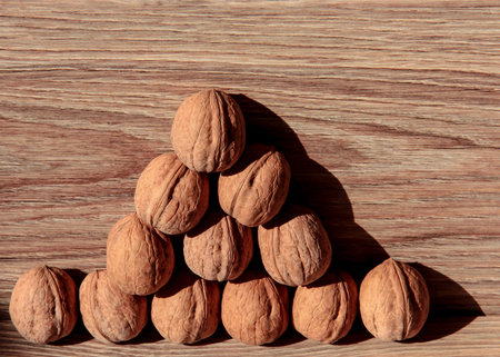Walnuts are laid out like a Christmas tree on a wooden background.