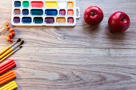On the wooden table are paints, brushes and plasticine.の写真素材