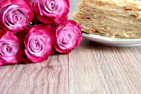 Roses with sweet pastries on a wooden table.の写真素材