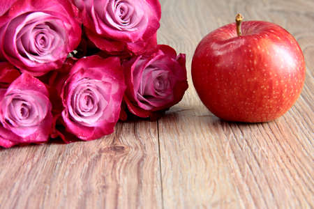5 pink roses on a wooden background with an Apple.の写真素材