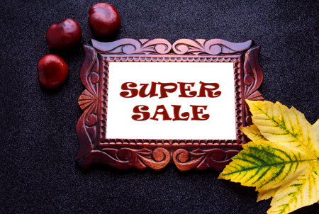 Wooden carved frame on a dark background with yellow leaves and the inscription: super sale.