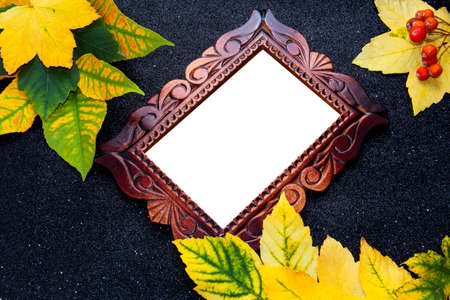 Wooden carved frame on a black background with autumn foliage.の写真素材