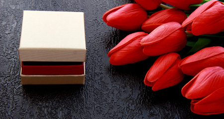 Tulips with a gift on a black background.