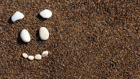 Smile on the sand. Funny face. Face of white stones.の写真素材
