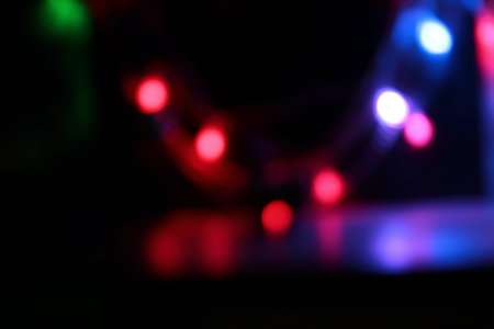 Bokeh on a black background. Colorful light bulbs are hanging.