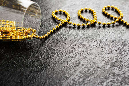Glass with gold beads on a black background.の写真素材