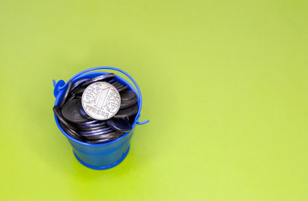 Bucket of coins. Blue bucket with Ukrainian money. Written in the Ukrainian language: 5 cents.の写真素材