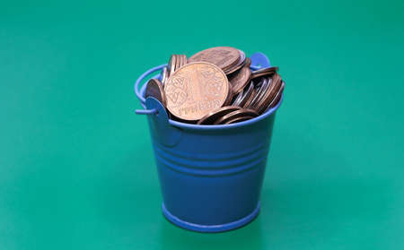 Bucket of coins. Blue bucket with Ukrainian money. Written in Ukrainian: 1 hryvnia.の写真素材