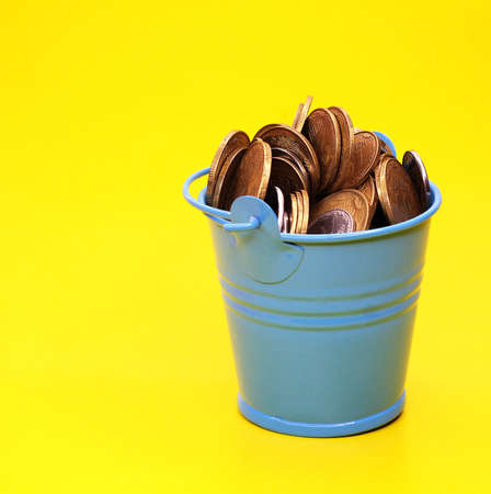 Bucket with coins on a yellow background. Ukrainian money.の写真素材