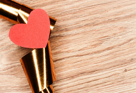 Red heart on a gold ribbon on a wooden background.の写真素材